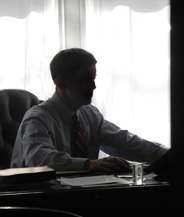 Walter McKee sits at his desk in silhouette